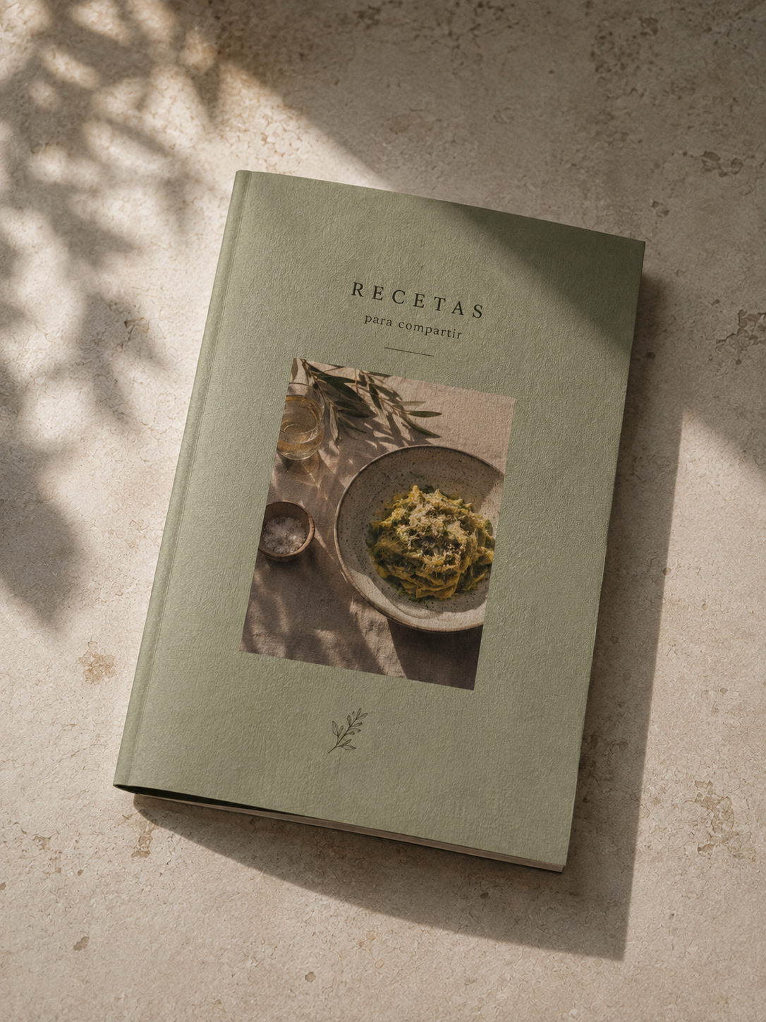 Fotolibro media carta con portada verde salvia y una fotografía centrada, sobre una mesa clara